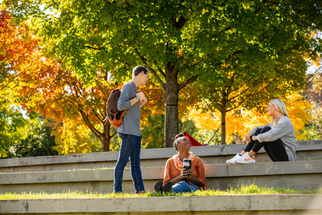 Three UT students chatting in the Humanities Ampitheatre on a nice fall day